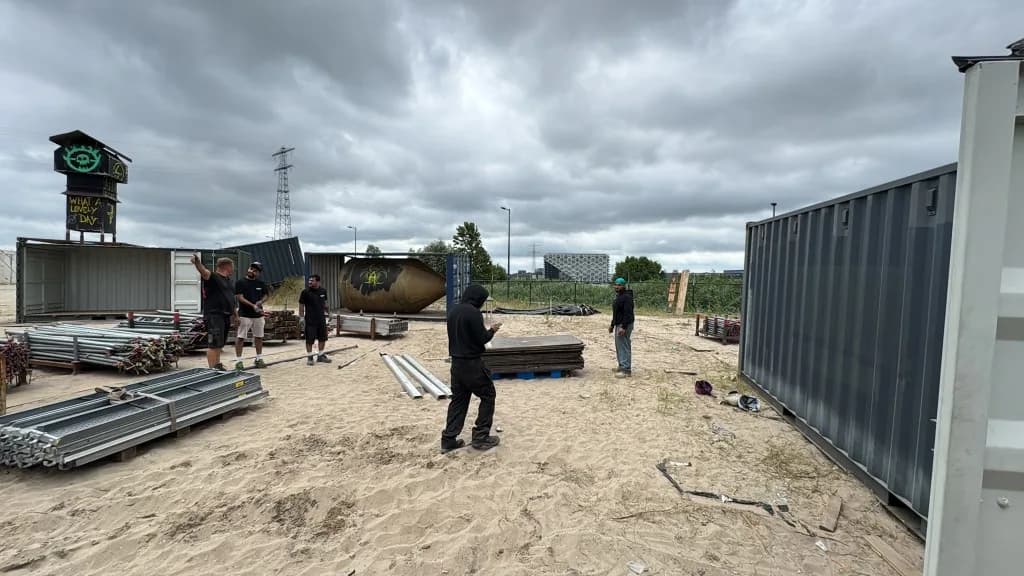 Festivalterrein tijdens opbouw met containers en crew