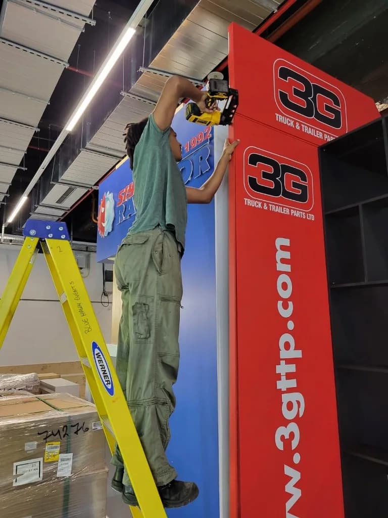 Crew bouwt een beursstand op met ladder en boormachine